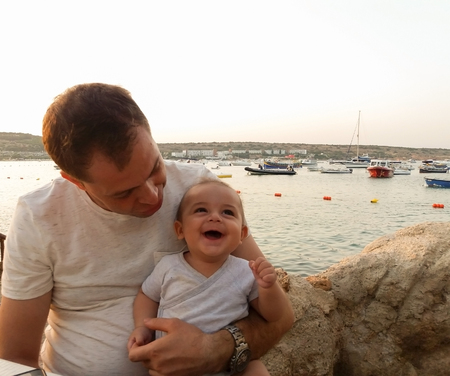 four month old baby boy sitting in the cafe on the beach, enjoying eveningの写真素材
