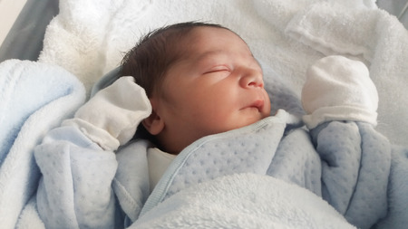 One day old newborn baby boy sleeping in hospital cotの写真素材