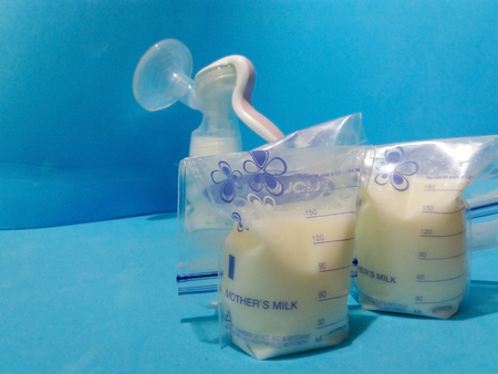 breast milk in storage bags with breast pump blue background