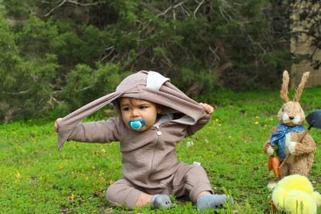 one year baby boy playing on the grass in rabbit suitの写真素材