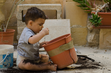 One and a half year old baby boy playing with dirtの写真素材