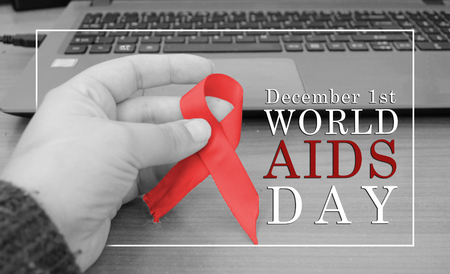 woman hand holding red ribbon for world aids day monochromeの写真素材