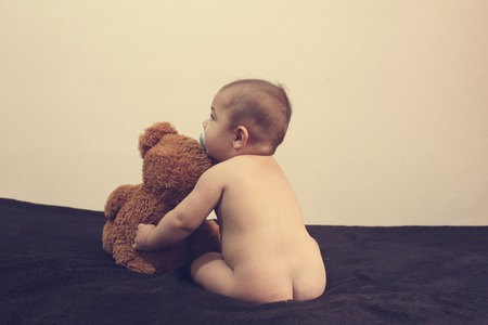 six months old naked baby boy huging teddy bear back view - best friends conceptの写真素材