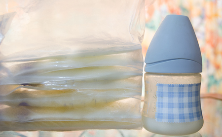 frozen breast milk in storage bags and baby bottle with fresh expresed milkの写真素材