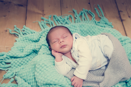4 weeks old newborn baby boy on green blanket sleepingの写真素材