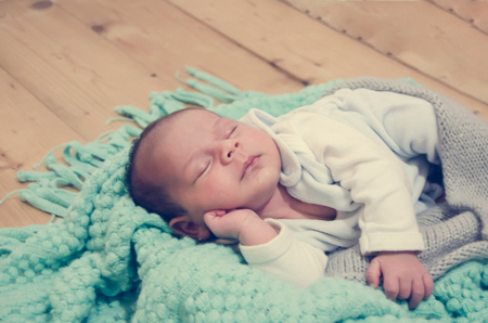 4 weeks old newborn baby boy on green blanket sleepingの写真素材