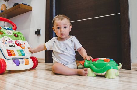 cute seven months old baby boy playing with educational toys on the floorの写真素材