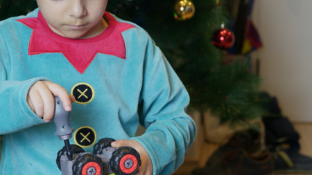 Cute boy elf assembling toys for kids in front of Christmas tree. High quality photoの写真素材