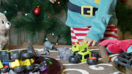Cute boy elf assembling toys for kids in front of Christmas tree. High quality photoの写真素材