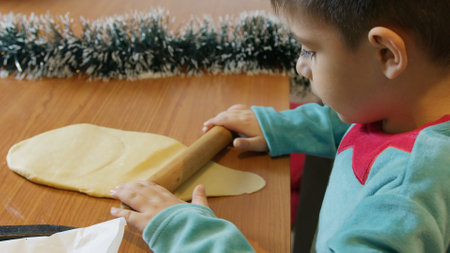 Adorable preschool boy in elf costume using rolling pin to make cookies. Christmas holidays. High quality photoの写真素材