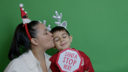 Mom and son invited Santa Claus to stop in their home with the Santa Stop Here sign and head decor. High quality photoの写真素材