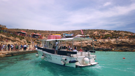 Comino, Malta 29.05.2024 - Moored Yacht in turquoise waters of Comino Islan Malta, summer vacation. POV from the boat, leaving the island. High quality photoのeditorial素材