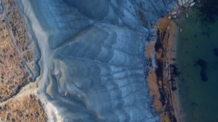 Clay cliffs flat rock cape Qarraba Bay, golden sand and emerald water in the early morning still in...