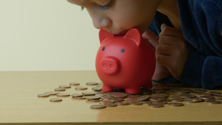 Child kissing his small red piggy bank. Child savings. High quality photoの写真素材