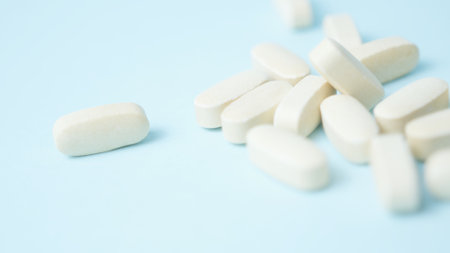 A bunch of white pills tablets on light blue background,. High quality photoの写真素材