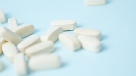 A bunch of white pills tablets on light blue background,. High quality photo