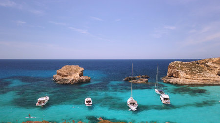 Comino, Malta 29.05.2024 - Boats anchored near Blue lagoon, Cominotto island in the back. Revealing shot. High quality photoの写真素材