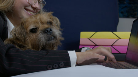 Young caucasian woman holding a dog pet and working from home on laptop. Remote classes or job. High quality photoの写真素材
