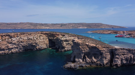 Aerial view of the sea caves of Cominotto uninhabited island near Comino, Maltese islands. Seagull flying in the frame. High quality photoの写真素材
