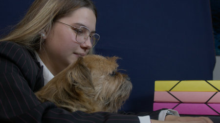 A vibrant office setting features a dog accompanying its owner while working at a laptop. The scene highlights companionship and a warm, productive work environment.の写真素材