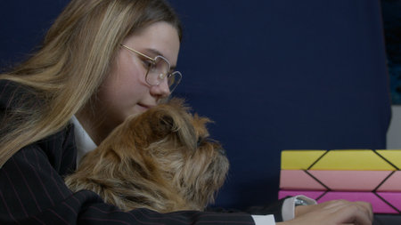 A young woman with glasses enjoys quality time with her small dog nearby a colorful object.の写真素材
