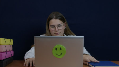 A professional woman sits at a desk working with documents, a laptop, and files. The scene conveys productivity and focus in a modern office environment.の写真素材