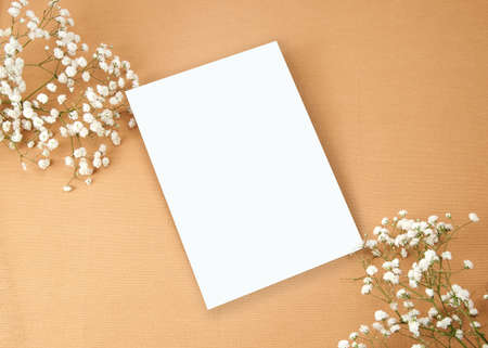 Invitation Mockup. Top view blank card on brown cloth background and flower with clipping path.の写真素材