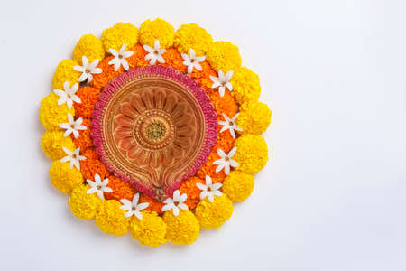 Flower Rangoli for Diwali Festival made using Marigold and leaf and Oil Lamp over white background,の写真素材