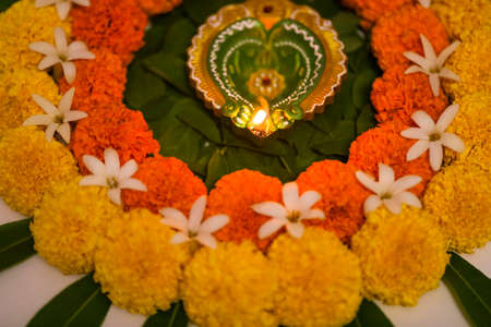 Flower Rangoli for Diwali Festival made using Marigold and leaf and Oil Lamp over white background,の写真素材