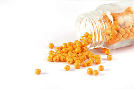 Beads spilling out from tiny glass bottle,on white isolated background,It is used in finishing fashion clothes. make bead necklace, beads for woman of fashion,Bead Crochet. Daily Beading.の写真素材