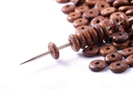 Wooden beads spread on white background with needle. Beads with needle . Close up, macro.の写真素材