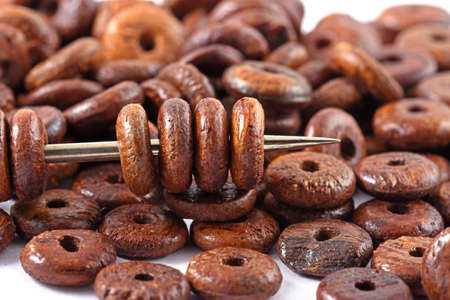 Wooden beads spread on white background with needle. Beads with needle . Close up, macro.の写真素材