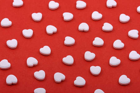 Heart shaped pills on a red background. Medicines that help people.