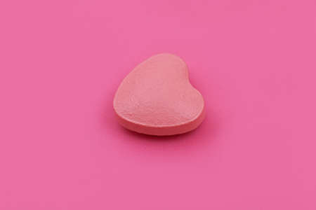 Heart shape Pharmaceutical medicine tablet on pink background,  Flat lay. Copy space. Medicine concepts. Minimalistic abstract concept. baby pink color backgroundの写真素材