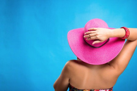 Woman wearing a sun hat, studio shot, blue backgroundの写真素材