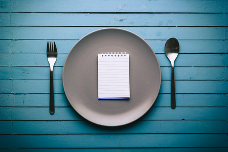 Empty plate with spoon and fork on the sides on a blue table, food conceptの写真素材
