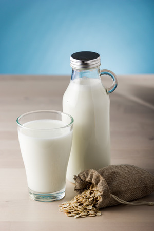Glass of milk and sack of oats on a wooden table and blue background. daily foodの写真素材