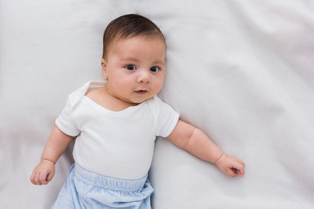adorable baby lying on a bed of white sheets