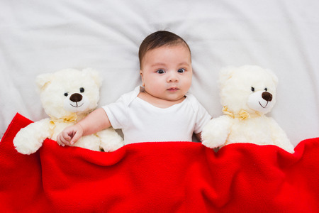 baby lying in his crib with his teddy bears aside
