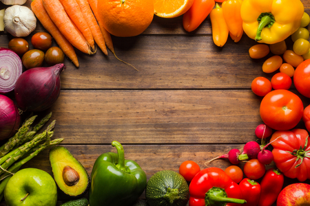 Frame of different types of fruits and vegetables on a wooden table with negative space to place logo or text.の写真素材