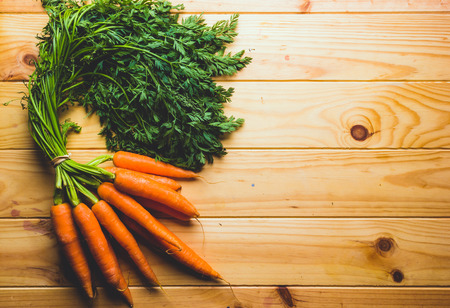 bunch of carrot on a pine wood table take out directly from the farm, top view.の写真素材