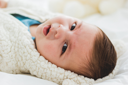 portrait of annoyed baby in his cribの写真素材