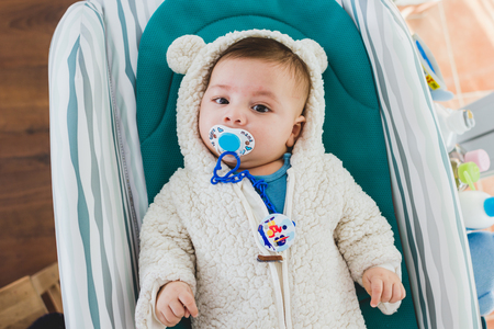 Face of adorable baby with pacifier in mouth looking at camera