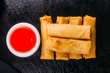 lumpias with sweet sauce on a black backgroundの写真素材