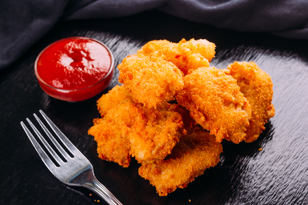 fried chicken on a black background and ketchup on the sideの写真素材