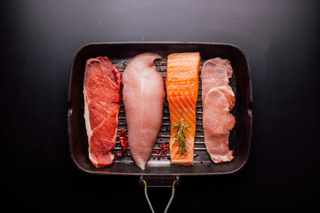 Group of animal proteins, chicken, meat, fish and pork on a black backgroundの写真素材
