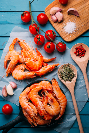 Top view of blue wooden table full of prawns and some ingredients for seasoning and vegetables to mix them, concept of recipes and restaurantsの写真素材