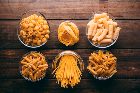 Top view of a rustic wooden table full of different types of pasta, Carbohydratesの写真素材