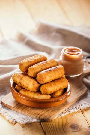Cheese fingers, typical Venezuelan appetizer called Teque?os accompanied with a pink sauce on a wooden boardの写真素材