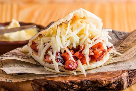 Arepa with fried pork and cheddar cheese ready to eat served on the tableの写真素材